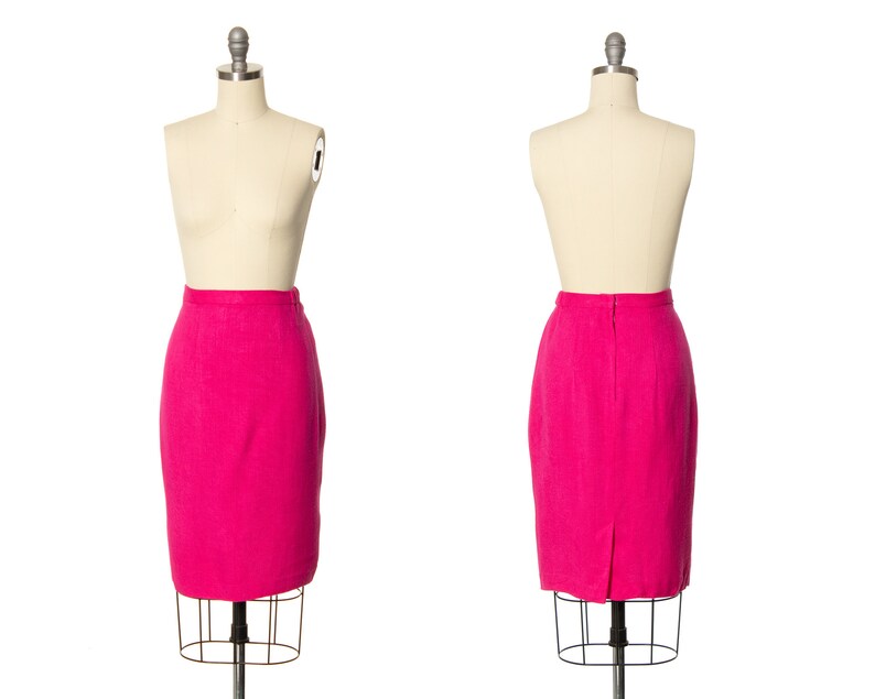 May include: A pink skirt on a dress form. The skirt is a pencil skirt and is made of a textured fabric.