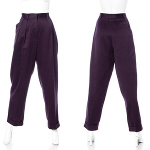 Pu&ograve; includere: Un paio di pantaloni viola a vita alta con pieghe sul davanti. I pantaloni hanno una vestibilit&agrave; rilassata e sono mostrati su un manichino.