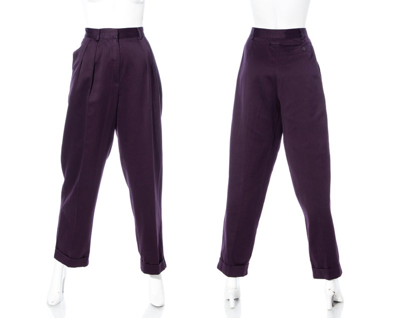 Pu&ograve; includere: Un paio di pantaloni viola a vita alta con pieghe sul davanti. I pantaloni hanno una vestibilit&agrave; rilassata e sono mostrati su un manichino.