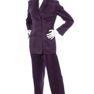 Pu&ograve; includere: Un completo viola a doppio petto con giacca a maniche lunghe e pantaloni abbinati.