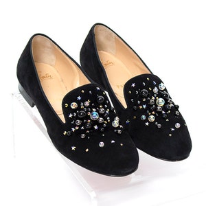 May include: Black suede loafers with a pointed toe and embellished with black and iridescent rhinestones. The loafers have a leather insole and a rubber outsole.