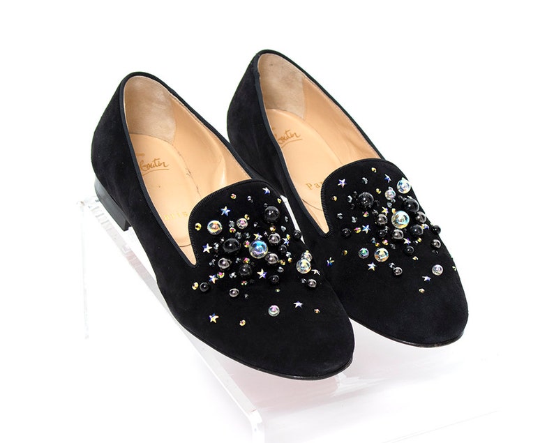 May include: Black suede loafers with a pointed toe and embellished with black and iridescent rhinestones. The loafers have a leather insole and a rubber outsole.