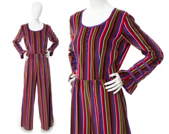 May include: A long-sleeved jumpsuit with a striped pattern in shades of purple, red, green, and white. The jumpsuit has a round neckline and long sleeves with wide cuffs. The fabric appears to be velvet.
