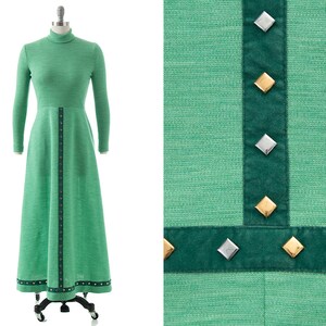 May include: A long green dress with a high neck and long sleeves. The dress has a dark green trim with silver and gold accents.