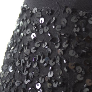 Puede incluir: Una falda negra con un dise&ntilde;o de lentejuelas. Las lentejuelas son peque&ntilde;as y redondas, y est&aacute;n dispuestas en un patr&oacute;n aleatorio. La falda est&aacute; hecha de una tela suave y fluida.