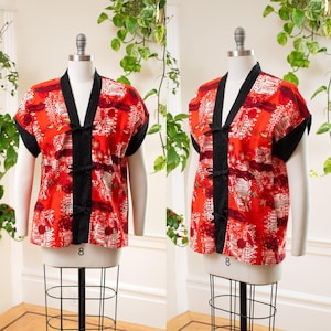 Puede incluir: Top estilo kimono rojo estampado, con ribetes negros y mangas cortas. El top presenta un cuello en V y cierres de nudo negro. La tela tiene un diseño floral blanco y rojo. La prenda se exhibe en un maniquí.