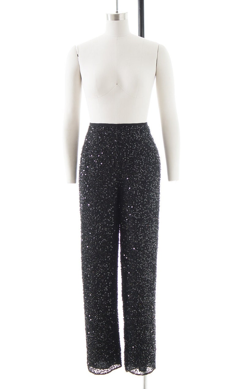 Puede incluir: Pantal&oacute;n negro de lentejuelas con cintura alta. El pantal&oacute;n est&aacute; hecho de una tela suave y fluida y est&aacute; adornado con peque&ntilde;as lentejuelas que crean un efecto brillante.