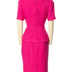 May include: A hot pink dress with a fitted bodice and a skirt that falls to the knee. The dress has a back zipper and short sleeves.