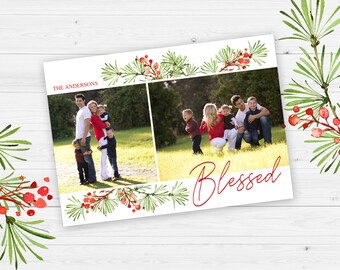 May include: A Christmas card template with a watercolor design of pine branches and red berries. The card features two photos of a family, one with the family standing together and the other with the family sitting on the grass. The text "The Andersons" and "Blessed" are written on the card.