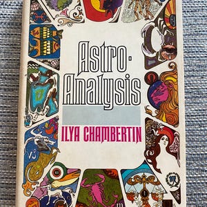 Könnte beinhalten: Ein Vintage-Buch mit dem Titel "Astro-Analysis" von Ilya Chamberlin. Das Cover hat einen weißen Hintergrund mit farbenfrohen Illustrationen von Tierkreiszeichen und Figuren. Der Titel ist in großen, fetten schwarzen Buchstaben gehalten, der Name des Autors in Rosa.