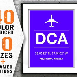 May include: A blue and white airport code print with the text "DCA" and the coordinates "38.8512° N, 77.0402° W" and the text "ARLINGTON, VIRGINIA".