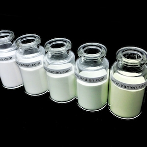 May include: Five glass jars with white powder inside. The jars have a white label with the text "www.Vadien.com" on them. The jars are arranged in a row from left to right, with the powder in each jar becoming progressively greener.