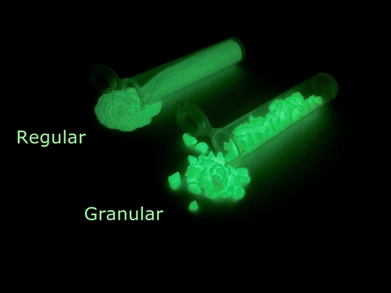 May include: Two test tubes filled with glowing green powder. The test tube on the left is labeled "Regular" and the test tube on the right is labeled "Granular".