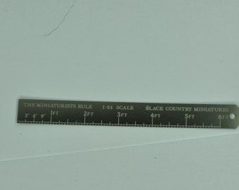 May include: A silver metal ruler with the text "THE MINIATURISTS RULE" and "BLACK COUNTRY MINIATURES". The ruler is marked with measurements up to 6 feet and is labeled "1:24 SCALE". It has a small hole at one end.