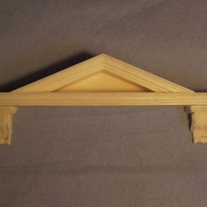 Può includere: Uno scaffale in legno con un top triangolare e decorazioni a volute sui lati. Lo scaffale è grezzo e pronto per essere dipinto o verniciato.