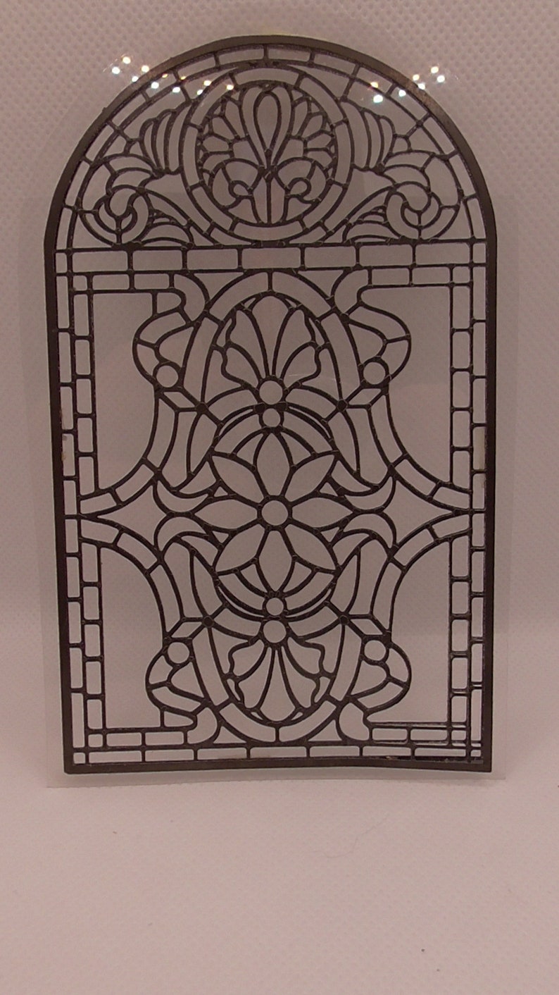 Peut inclure: Un motif de fen&ecirc;tre en vitrail noir avec un motif floral. Le motif est en forme d'arche et pr&eacute;sente un motif r&eacute;p&eacute;titif de fleurs et de feuilles.