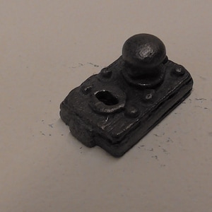 Könnte beinhalten: Ein schwarzer Türknauf aus Metall mit einem runden Griff und einem Schlüsselloch. Der Knauf ist auf einer rechteckigen Metallplatte montiert.