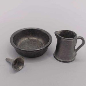 Puede incluir: Un juego de tres utensilios de cocina en miniatura hechos de metal. El juego incluye un tazón pequeño, una jarra y un embudo. Los tres artículos son de color gris oscuro.