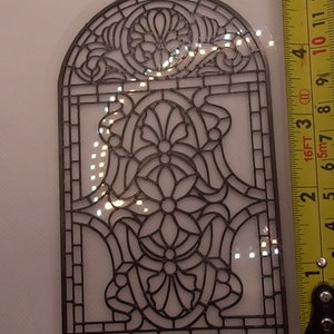 Peut inclure: Un motif de fen&ecirc;tre en vitrail en m&eacute;tal noir avec un motif floral. Le motif mesure environ 25 cm de haut et 15 cm de large.