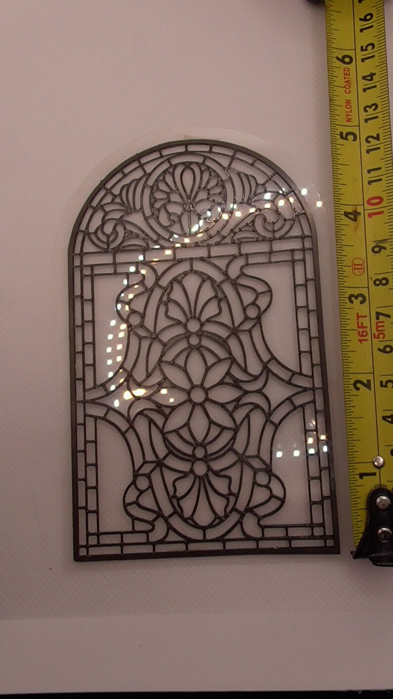 Peut inclure: Un motif de fen&ecirc;tre en vitrail en m&eacute;tal noir avec un motif floral. Le motif mesure environ 25 cm de haut et 15 cm de large.