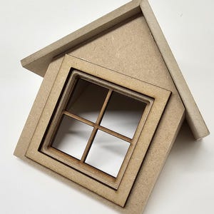 Peut inclure: Une petite maison en bois avec un toit à pignon et une fenêtre carrée. La fenêtre est divisée en quatre carreaux. La maison est en bois brun clair et a un design simple. La maison est légèrement inclinée, donnant une sensation de dynamisme.