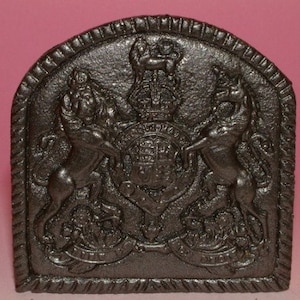 Peut inclure: Un garde-feu en fonte noire avec un design détaillé d'un blason royal comportant deux lions et une couronne.