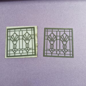 May include: Two square, olive-green decorative cutouts with an Art Deco design. One cutout is on a white background, the other is a standalone cutout. The design features stylized floral elements and geometric lines.