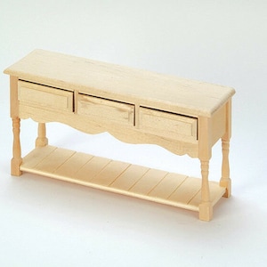 Könnte beinhalten: Ein Konsolentisch aus Holz mit drei Schubladen und einem unteren Regal. Der Tisch hat eine helle Holzoptik und gedrehte Beine.