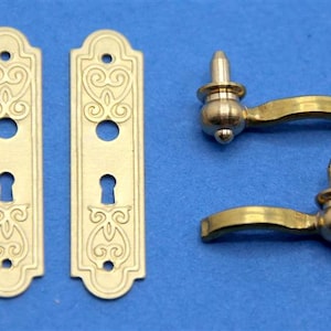 May include: Two ornate gold door plates with keyhole cutouts and two matching gold door handles with a rounded knob and a curved lever.