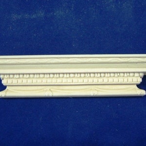 May include: A white decorative moulding with intricate details, featuring a beaded border and a scalloped edge. This moulding is ideal for adding a touch of elegance to any room.