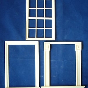 May include: Three white wooden window frames, one with a grid of 12 squares and two with simple rectangular frames.