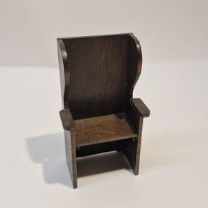 May include: A small, dark brown wooden chair. The chair has a high back, armrests, and a seat. It is designed for a doll's house or miniature setting. The chair's dimensions are suitable for a small-scale model.