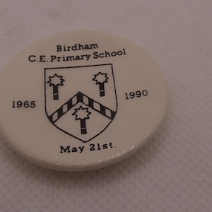 May include: White ceramic round button with black text and a black and white crest. The text reads "Birdham C.E. Primary School" and "1965" and "1990" and "May 21st."