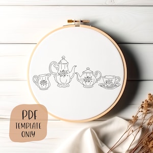 May include: A black and white line drawing of a tea set on a white background. The set includes a teapot, a creamer, a sugar bowl, and a teacup and saucer. The tea set is in a wooden embroidery hoop.