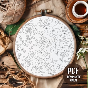 May include: A white embroidery hoop with a floral design in black outlines. The design features various flowers and leaves. The text "PDF TEMPLATE ONLY" is in a brown circle. The hoop is on a wooden surface.