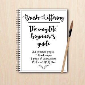 K&ouml;nnte beinhalten: Ein wei&szlig;es Spiralblock mit dem Titel "Brush Lettering: Der komplette Anf&auml;ngerleitfaden" und Details &uuml;ber die Anzahl der &Uuml;bungsseiten, linierten Seiten und Anleitungen. Ein Pinsel liegt auf dem Block.