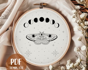 Può includere: Un telaio da ricamo color crema con un disegno di falena nera con fasi lunari. Il disegno include stelle e simboli a croce. Il testo "PDF TEMPLATE ONLY" è in un cerchio marrone.