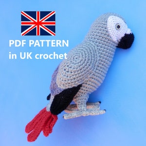 Puede incluir: Un loro gris de crochet con cola roja y pico negro. El loro está sentado sobre un fondo azul. PDF PATTERN in UK crochet.