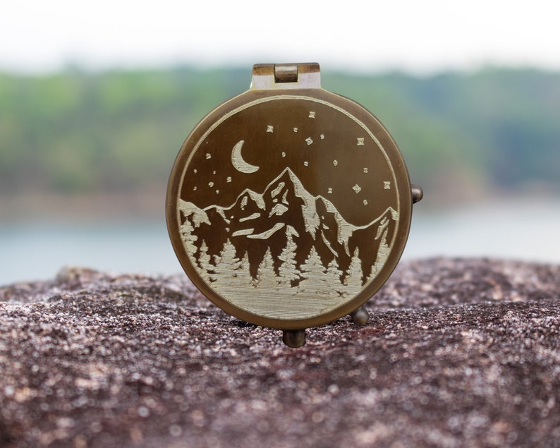 engraved compass with mountain moon and stars