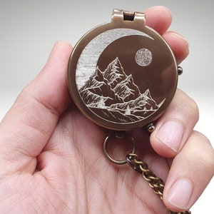 engraved compass with mountain moon and stars