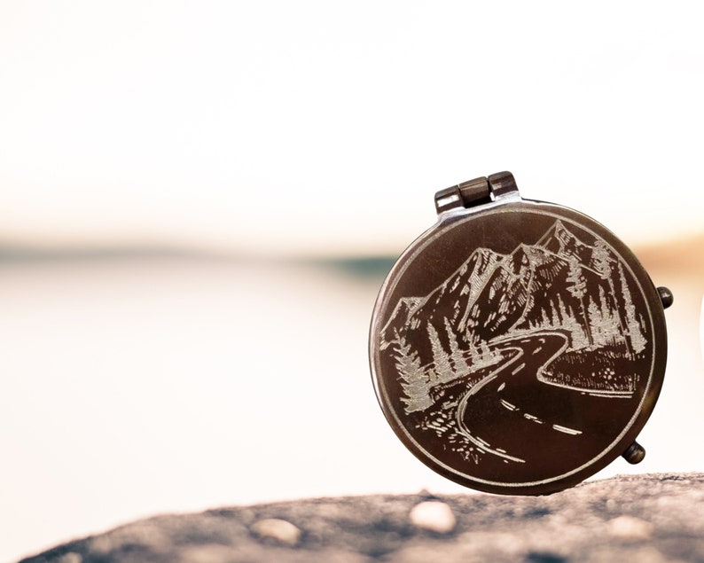 engraved compass with mountains and road