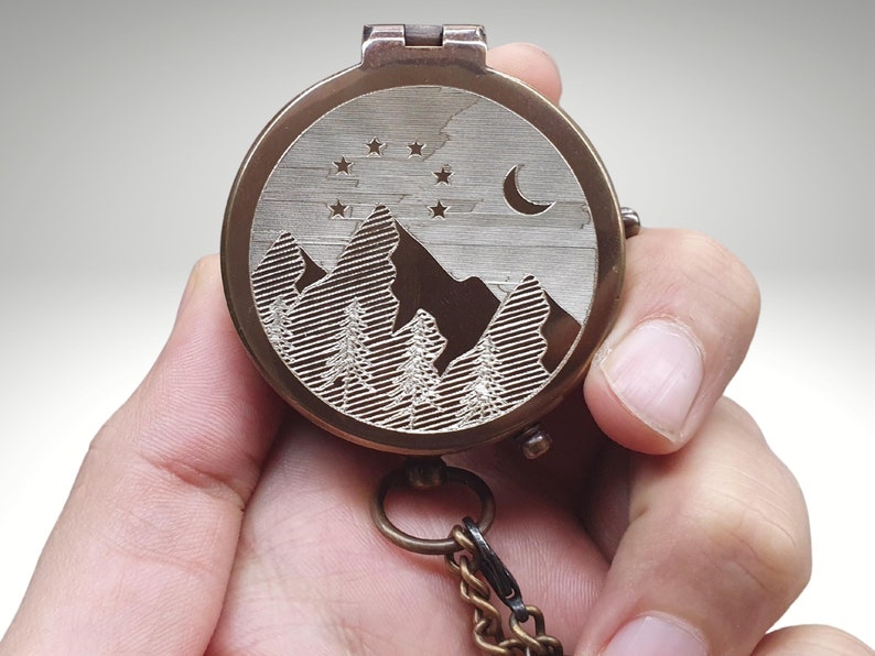 engraved compass with mountain moon and stars