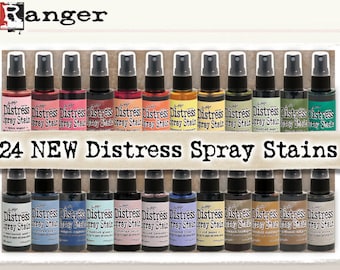 May include: A collection of 24 new Distress Spray Stains in various colors. The bottles are arranged in two rows of 12, with the text "24 NEW Distress Spray Stains" printed on a banner in front of the bottles.