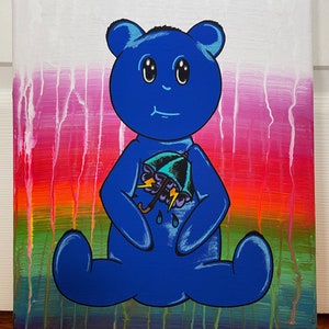 May include: A blue teddy bear with a worried expression holds a teal umbrella with lightning bolts and raindrops. The background is a colorful gradient of pink, orange, yellow, green, and purple.