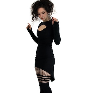 May include: A black dress with a high neckline and a cut-out detail at the chest. The dress has a high-low hemline and is paired with black fishnet tights and black platform boots.
