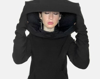 May include: A black hooded sweatshirt with a large, oversized hood that can be pulled over the head. The hood is made of a thick, soft fabric and has a relaxed fit.