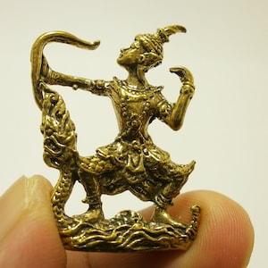 May include: A gold-colored figurine of a mythical creature with a human-like figure holding a bow and arrow. The creature is standing on a base with a wave-like design.