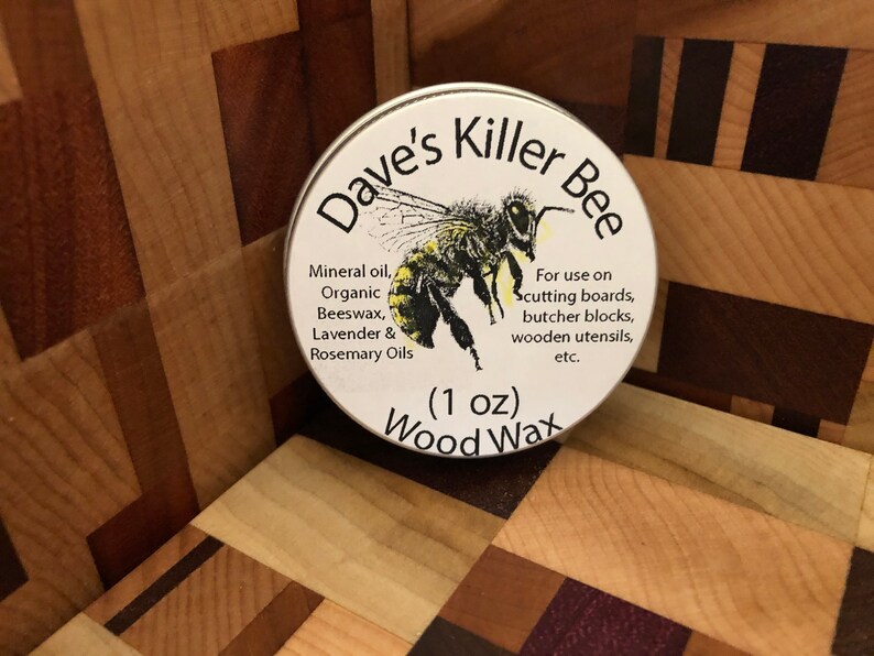 May include: A white tin with a yellow and black bee illustration and the text "Dave's Killer Bee Wood Wax (1 oz)". The tin contains a wood wax for use on cutting boards, butcher blocks, wooden utensils, and more.