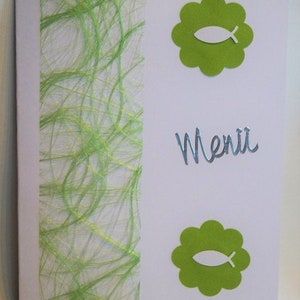 Può includere: Biglietto del menu bianco con dettagli floreali verdi e un simbolo di pesce. La parola "Menu" è scritta in corsivo. Una striscia verde strutturata corre verticalmente sul lato sinistro.