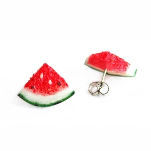Peut inclure: Une paire de boucles d'oreilles en forme de tranche de pastèque avec des tiges argentées. Les boucles d'oreilles sont en pâte polymère et peintes pour ressembler à une tranche de pastèque.